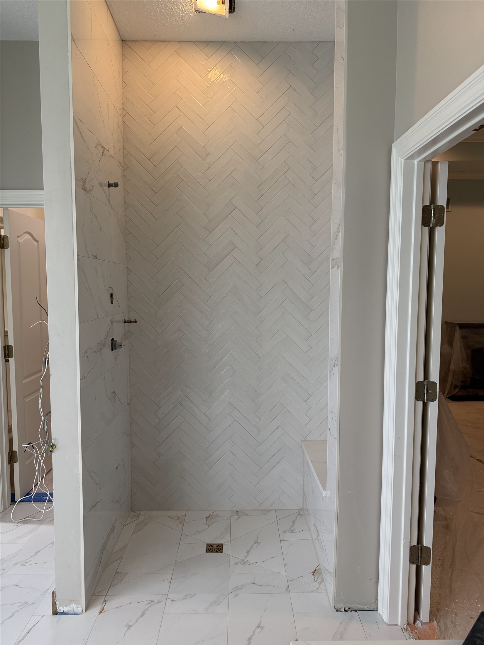 Herringbone shower walls installed by Heartland Tile